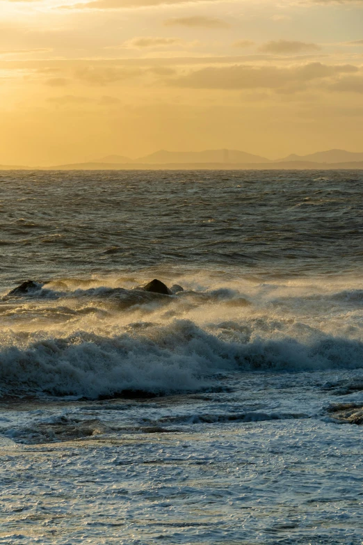 there is an ocean sunset with waves coming in