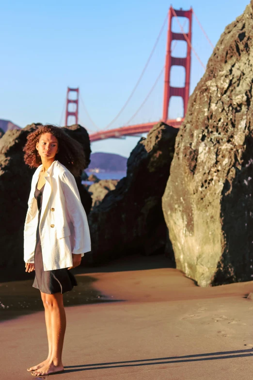 a woman in white blazer standing near large rocks