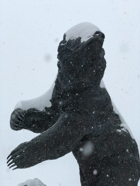 a statue sitting in the snow in front of a building