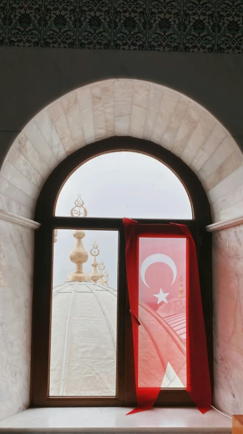 two flags, two red banners, and a white wall under a window