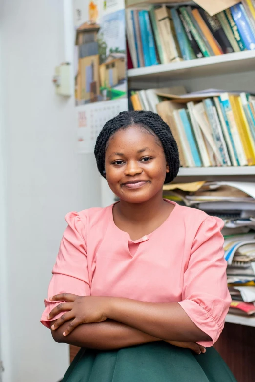 a black woman sits in front of a bookshelf