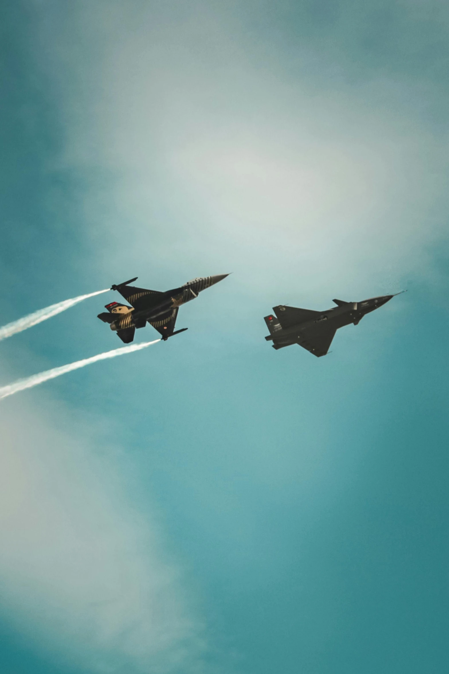 two fighter jets flying through a blue sky