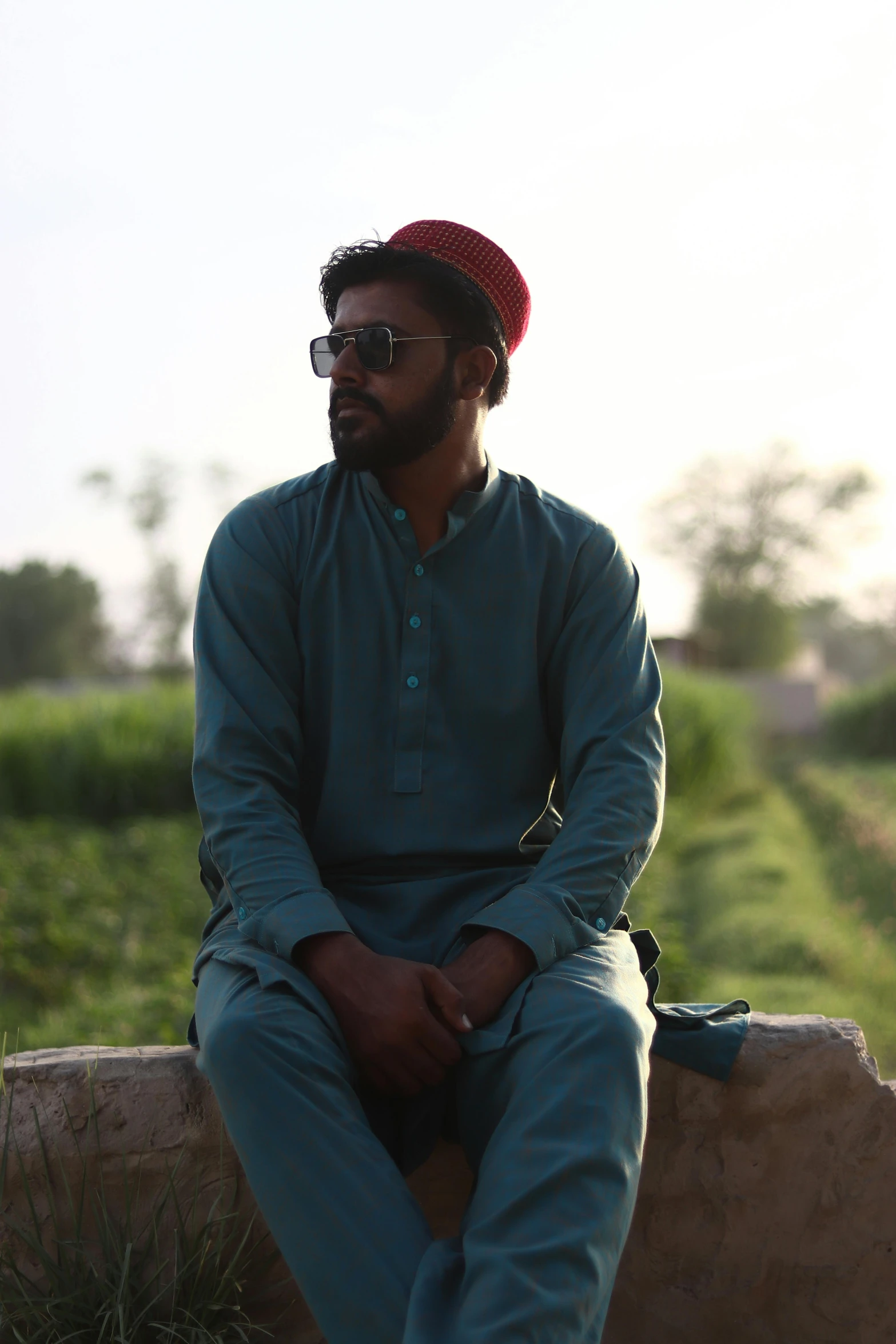 a young man is sitting down in the grass