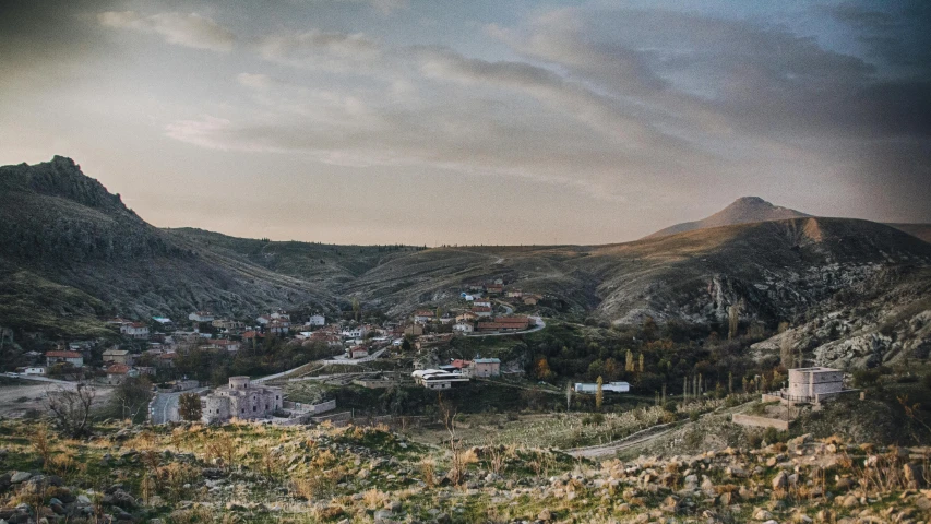 the hills are covered in shrubs and there is a town at the base