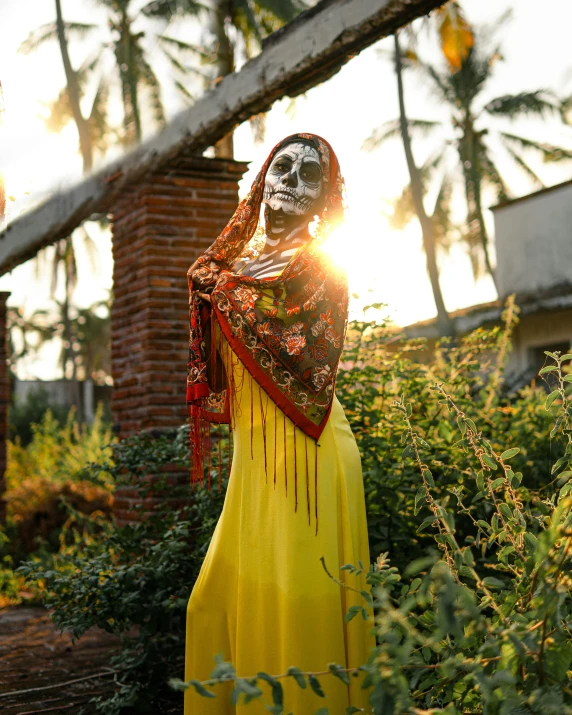 a woman is dressed in yellow and a skeleton face mask