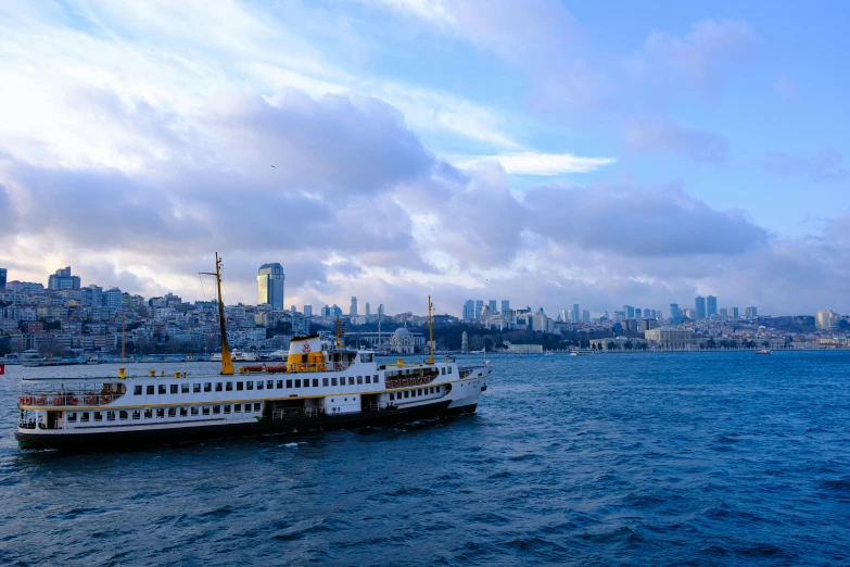 a ferry boat in the water near buildings on a cloudy day