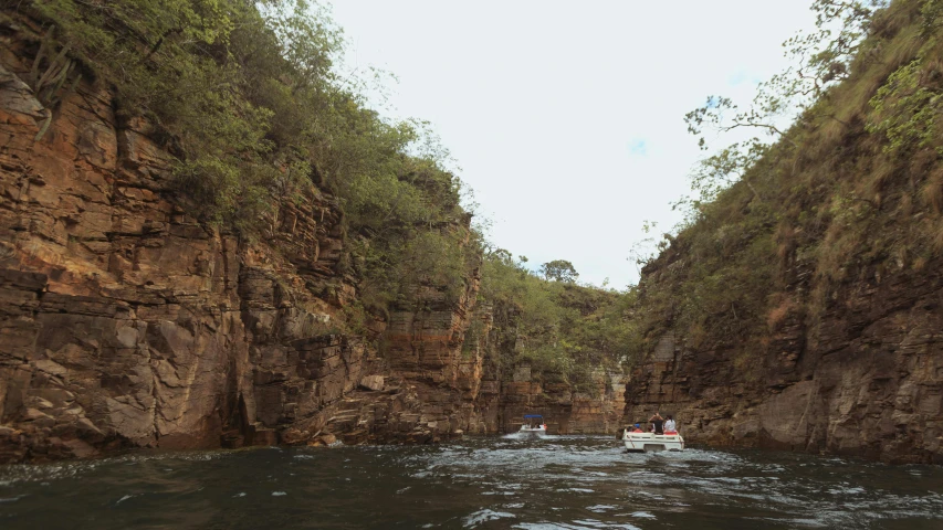 people are on boats in the canyon near mountains