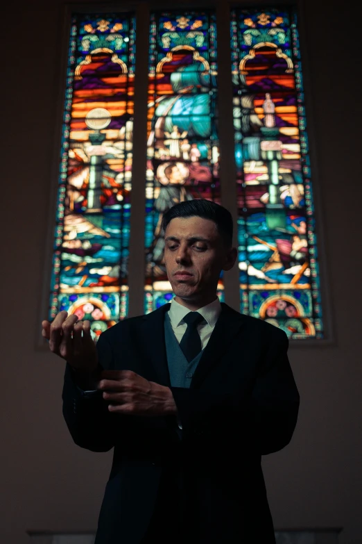 a man stands in front of the stained glass windows