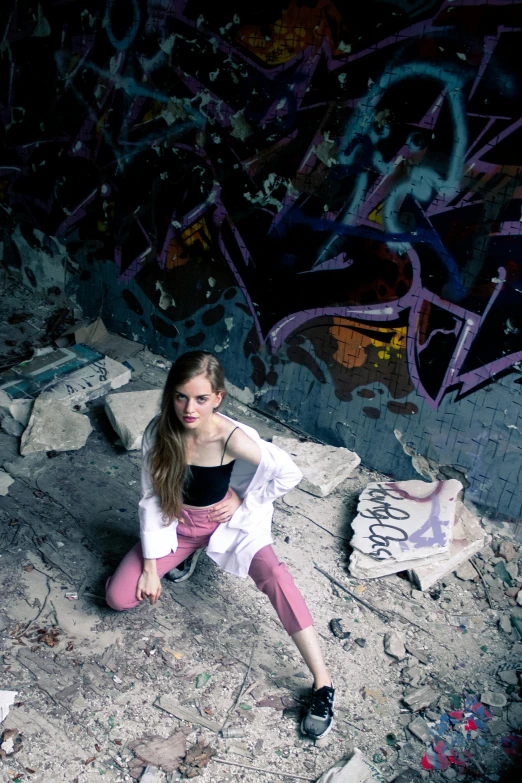 a young woman sitting on the ground in front of a graffiti wall