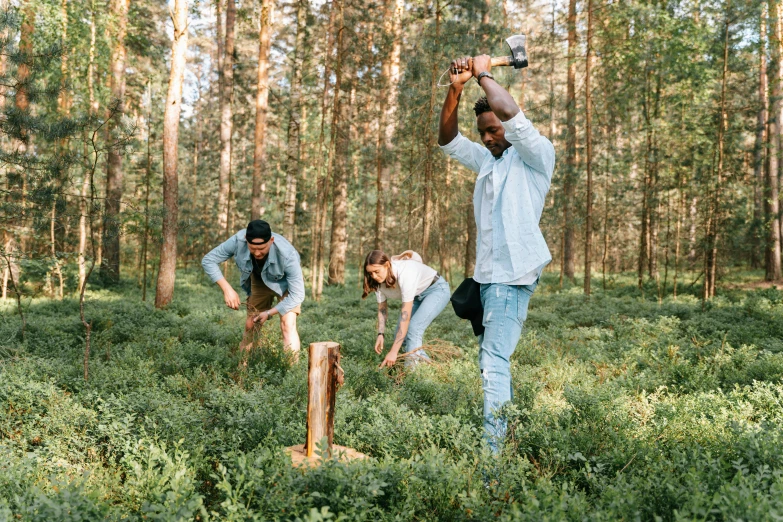 three men stand in the woods playing with a bat