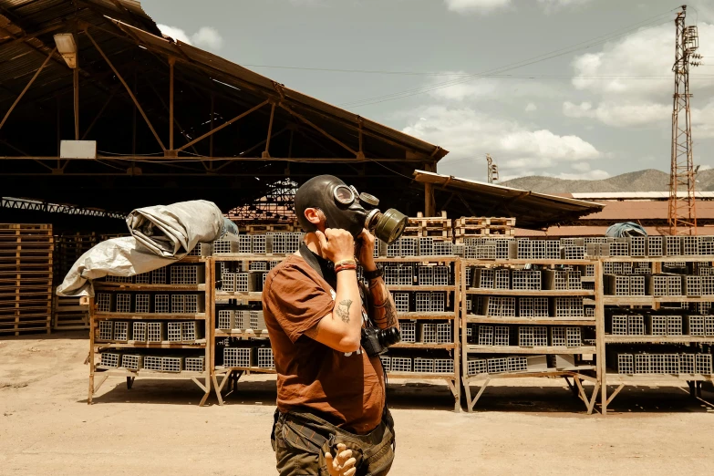 a young man holding a camera while standing in front of a lot of stacked boxes