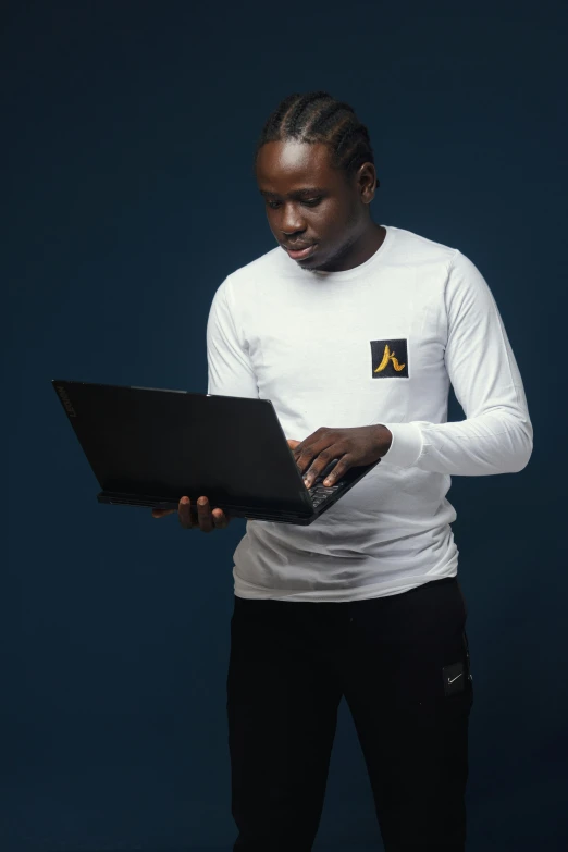 an african american man wearing a white shirt with a black and yellow logo on it using his laptop