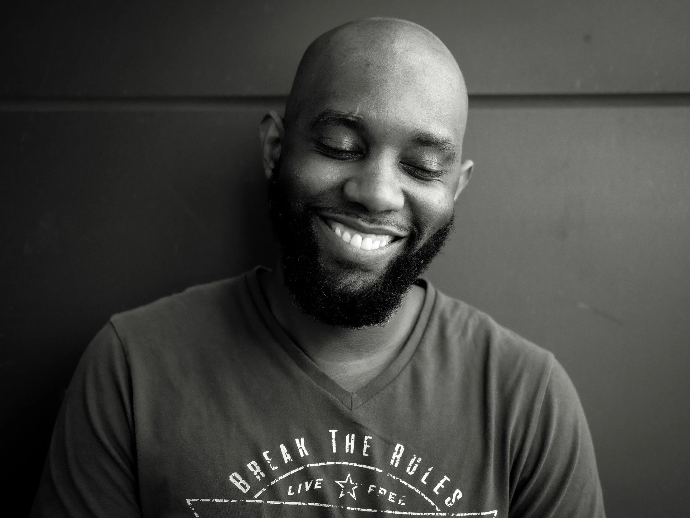 man laughing for the camera in front of wall