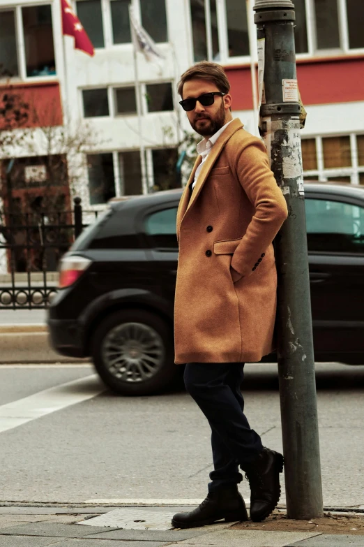 man leaning on a street lamppost posing for a po