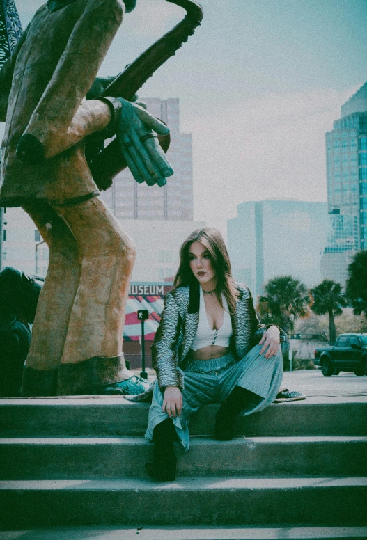 woman sitting on steps looking up to a statue