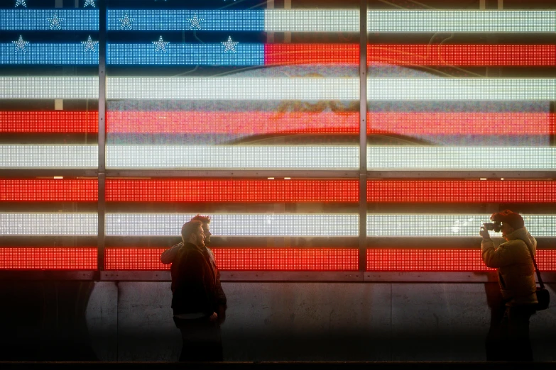 two women are looking at an american flag projected on a wall