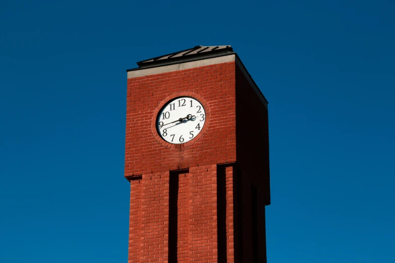 clock on the top of a red brick building with sky in background