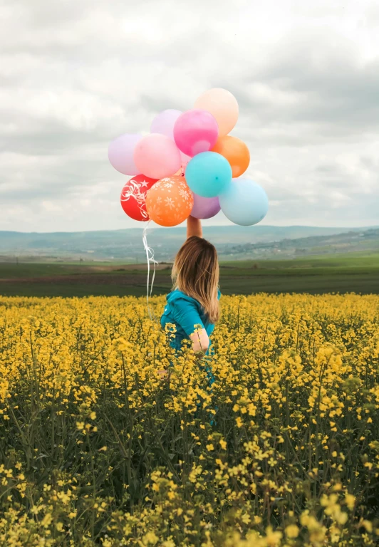 girl holding colorful balloons with mountains in the background