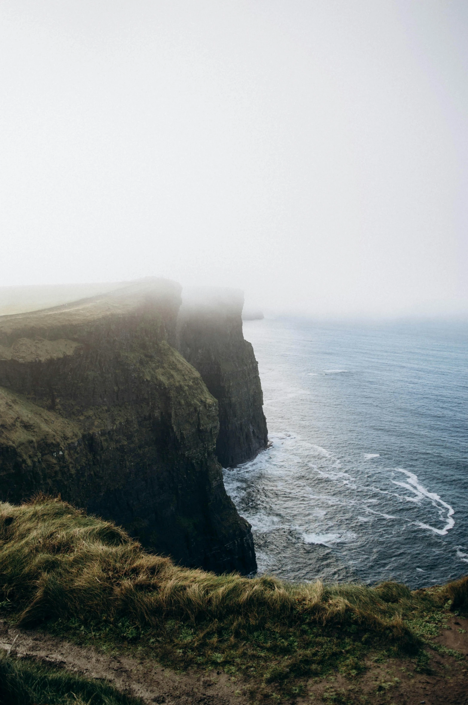 the cliff is next to the ocean on a foggy day