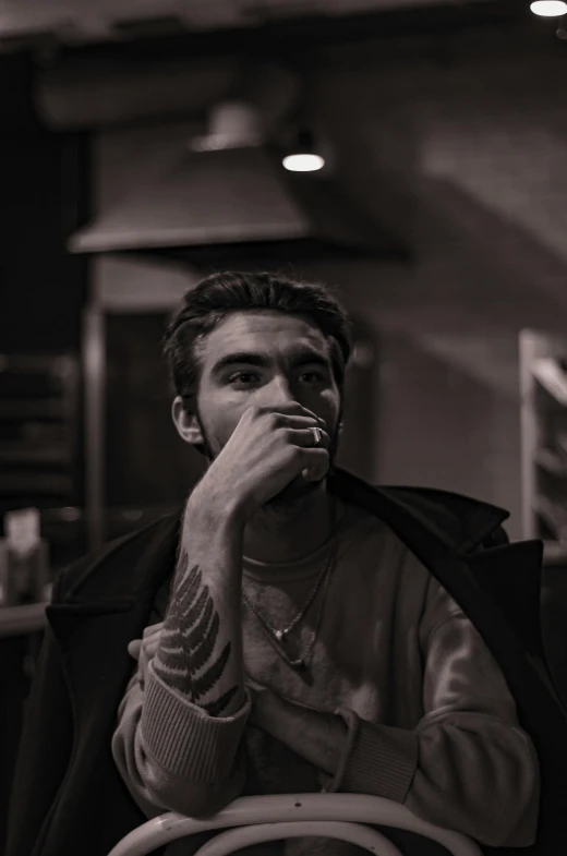 a person sitting at a table drinking from a cup