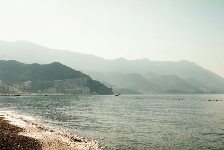 an empty beach by the water with mountains in the background