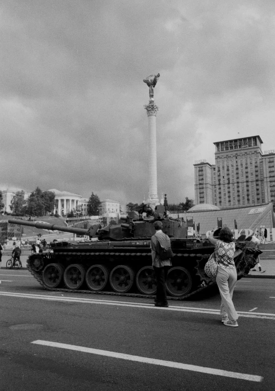 some people and tanks on a street near some buildings