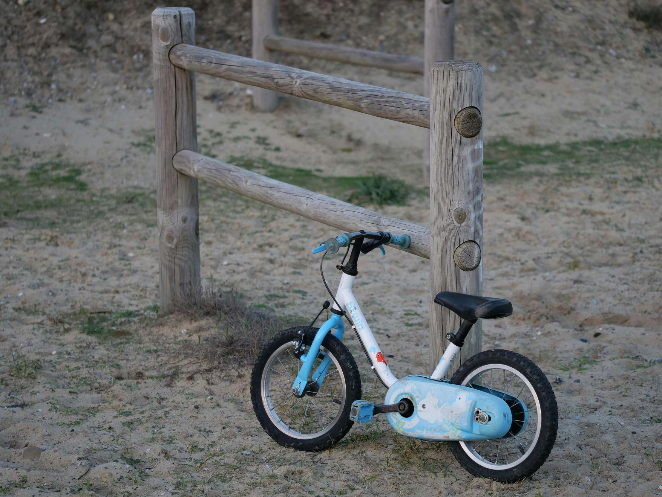 a small bike is standing by a fence