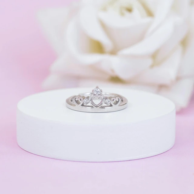 the wedding ring sits on top of a box next to a white rose