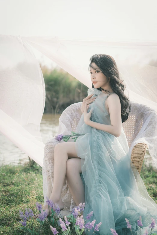 a woman sitting on top of a wicker chair next to a flower field