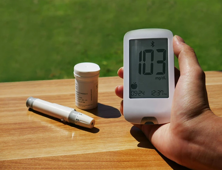 person is holding up an electronic thermometer and two bottles on a table