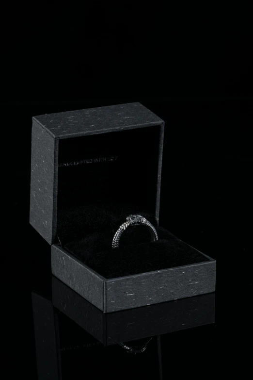 a ring sits inside of a box on a black surface