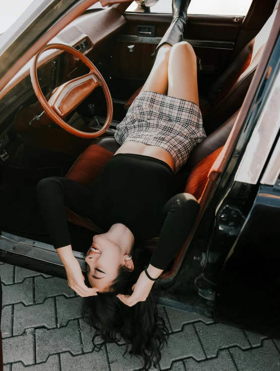 a girl wearing shorts and black shirt on the ground by a car door