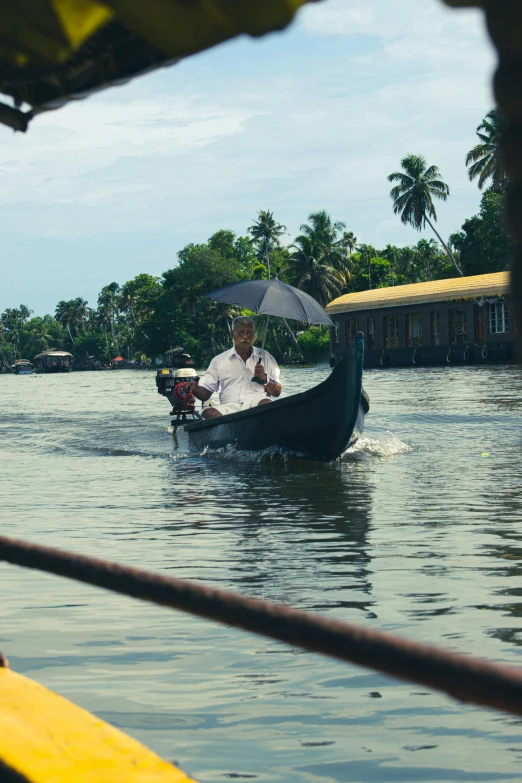 a man is holding an umbrella while in a boat on a body of water