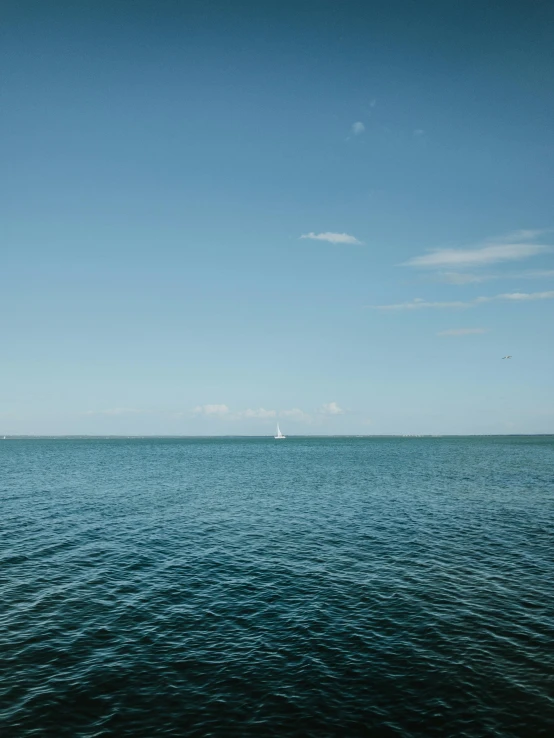 an image of blue water with a sailboat in it