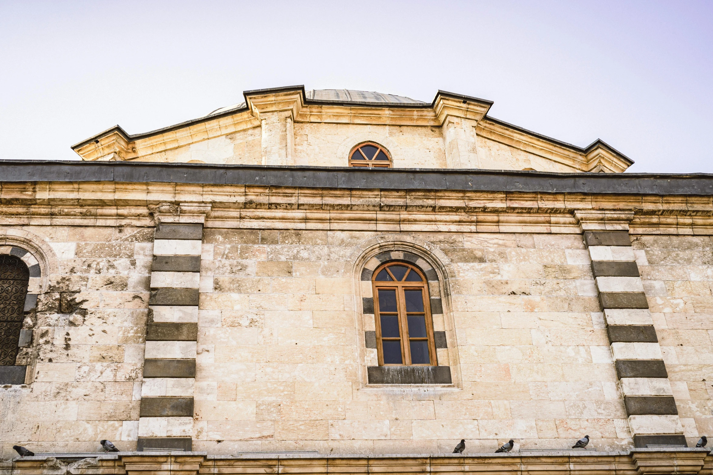 a stone building has pigeons on it and an open window