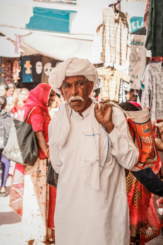 a man with a white mustache is walking in front of a store