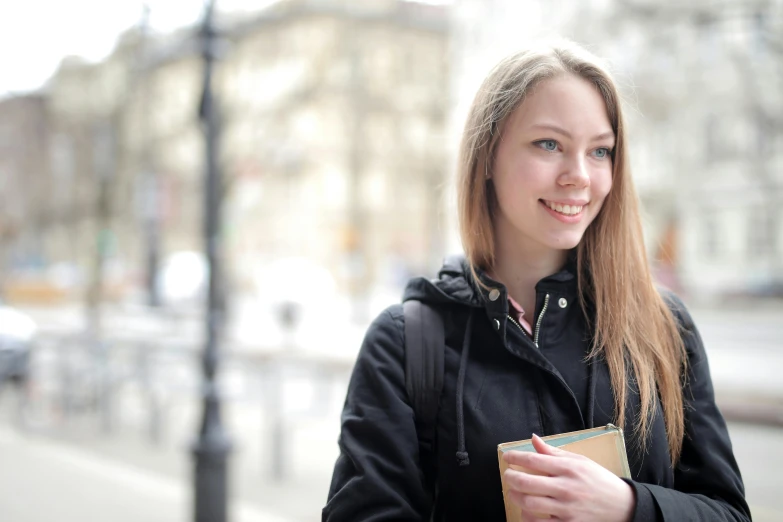 a young woman holding a brown bag while standing next to a street