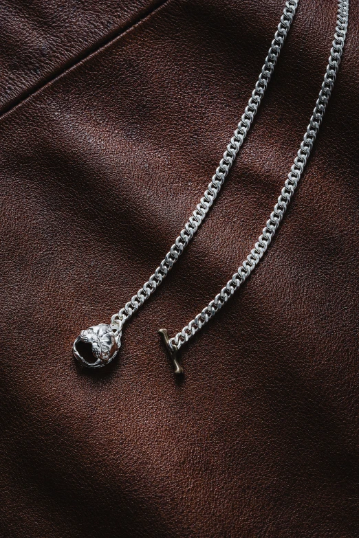 a necklace and a chain laying on top of a brown blanket