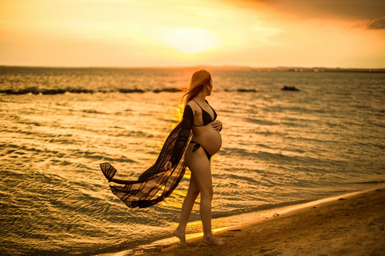 woman in black bikini wearing scarf walking on beach