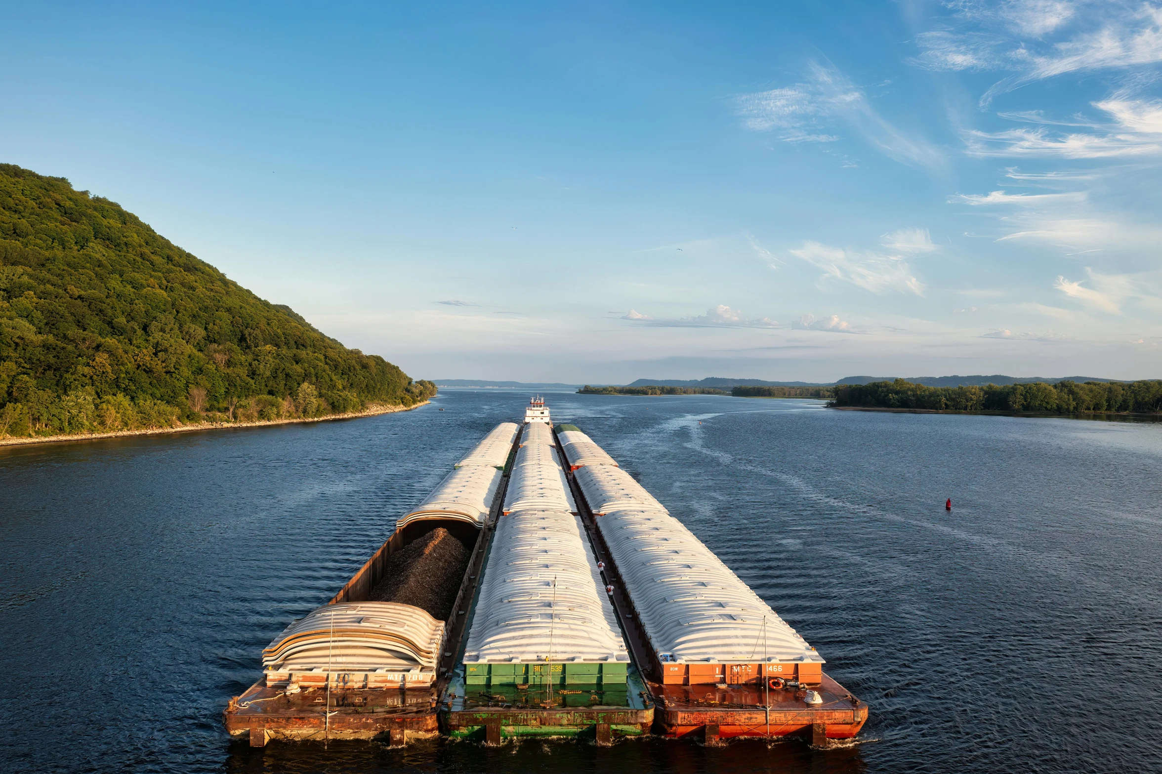 two large tankers crossing a canal in front of a mountain