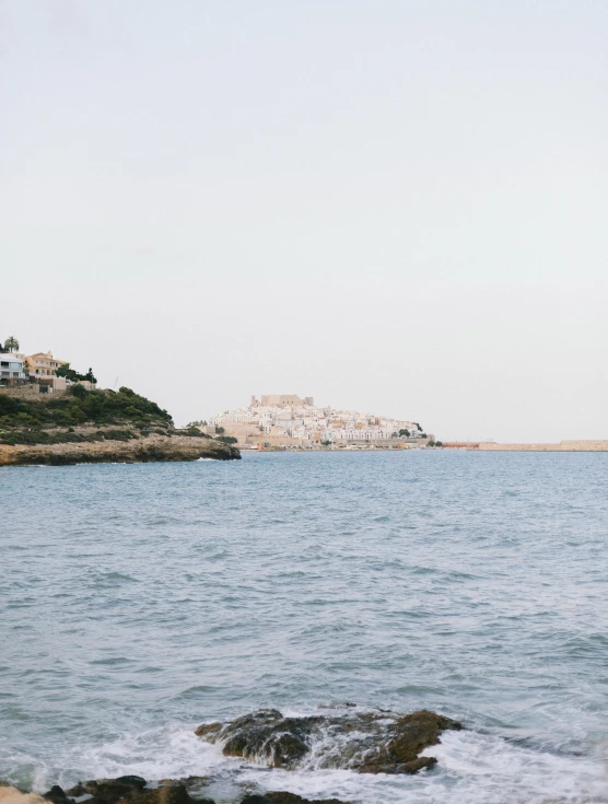 a bird flying over the ocean with rocks