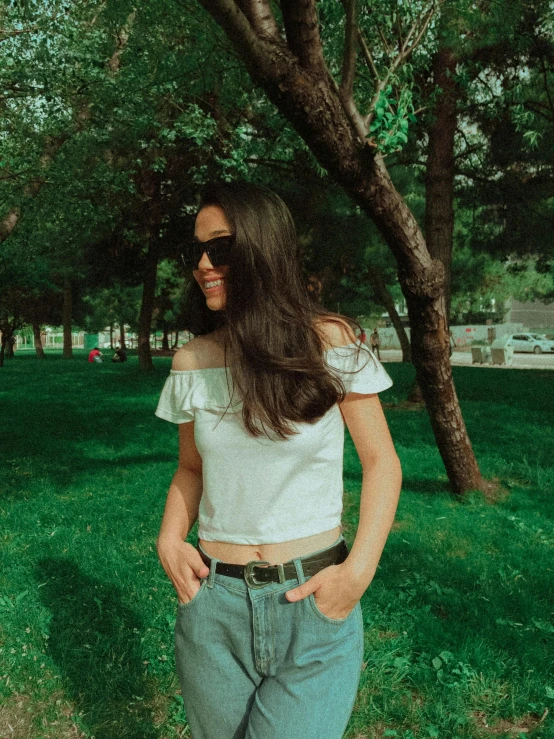 a woman is posing under some trees in the park