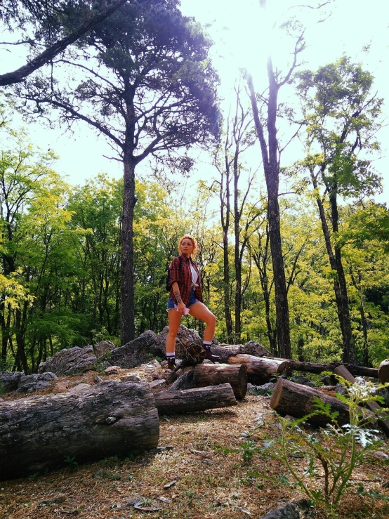 the man is walking across logs in the woods