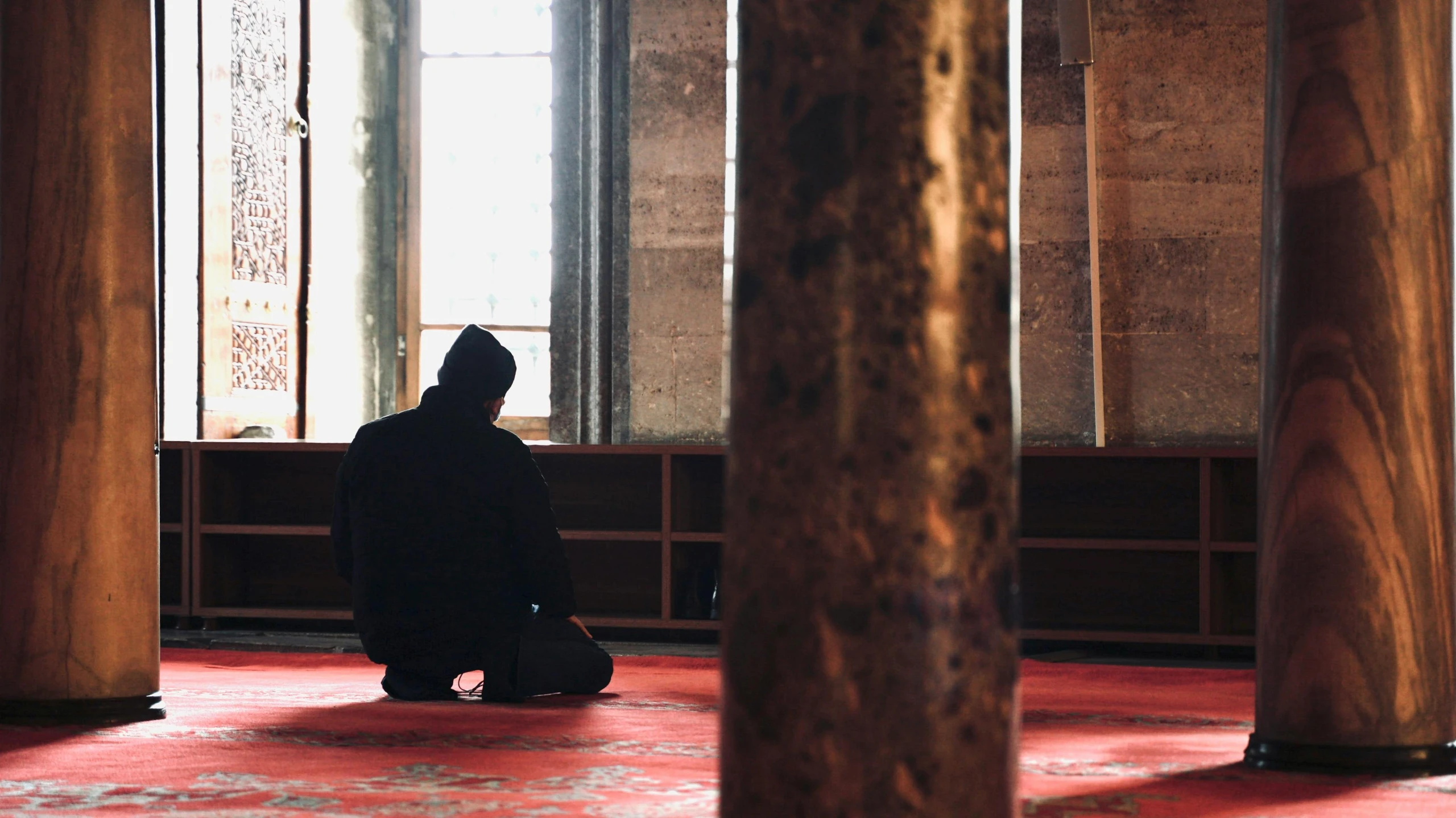 a person in black sitting on the floor of a room