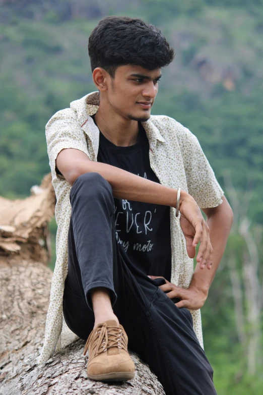 a young man is sitting on a rock