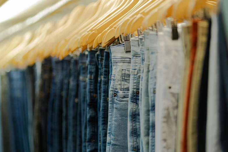 a row of blue jean pants on the clothes rail