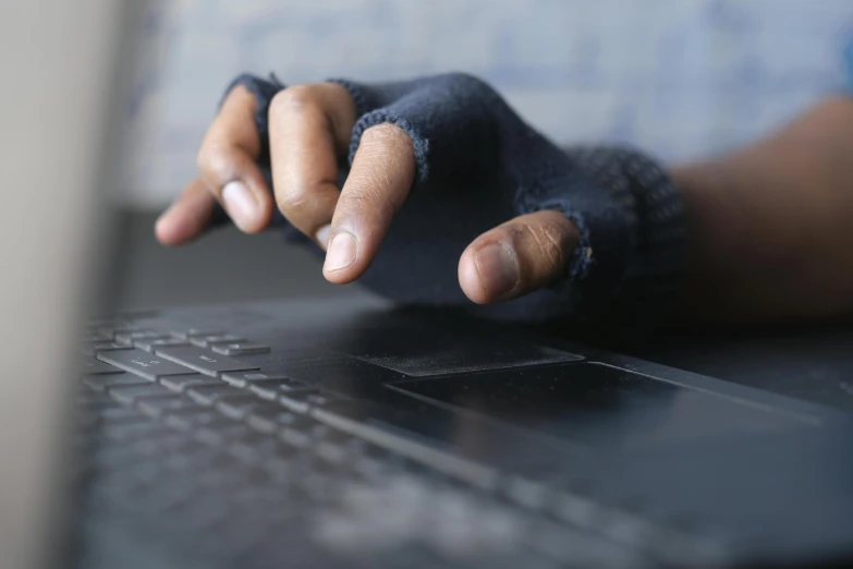 a person in blue gloves touching their finger on a laptop computer