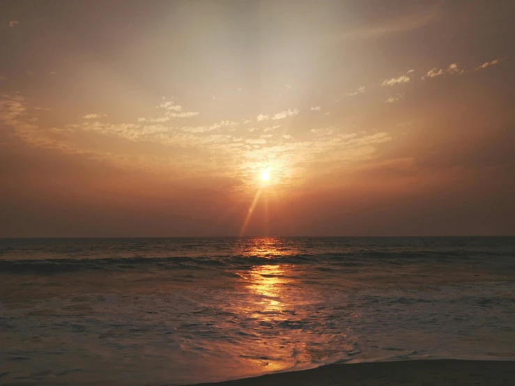 the sun rises over the ocean during low tide