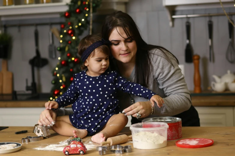 an adult with a child and several cooking supplies