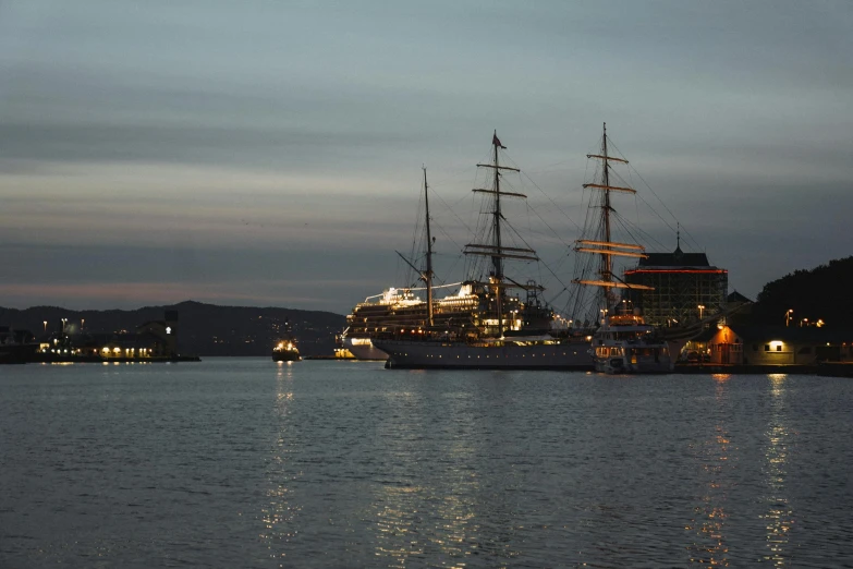 some ships are floating along the water by a dock